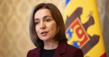 Moldovan President Maia Sandu speaking in front of the national flag.