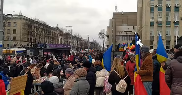 A crowd of protesters holding Moldovan flags in a street in Chisinau.