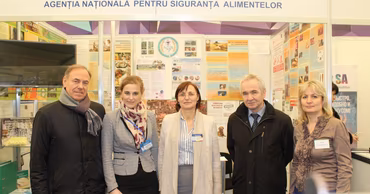 Group of ANSA officials standing in front of their agency booth at an exhibition.