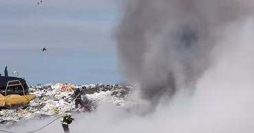 Firefighters working to extinguish a large fire at a waste landfill site.
