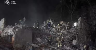 Emergency workers searching through the rubble of a destroyed building in Kyiv at night.