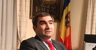 Portrait of prosecutor Octavian Pavlovschi in front of a Moldovan flag.