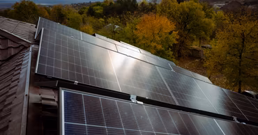 Solar panels installed on a residential roof in a rural setting.