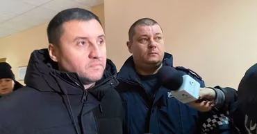 Two men being interviewed by a journalist in a hallway, likely at a courthouse.