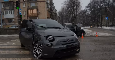 A damaged grey Fiat car at a street intersection after a traffic accident.