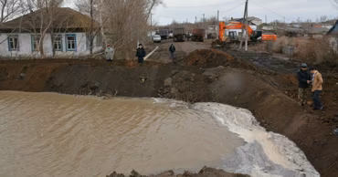 Construction machinery and workers building a temporary earth dam to manage floodwaters.