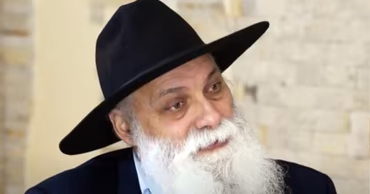 Artur Cerari, the former baron of the Roma in Moldova, wearing a black hat and white beard.