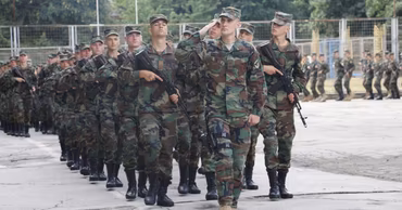 Moldovan soldiers in camouflage uniforms marching during a military ceremony.