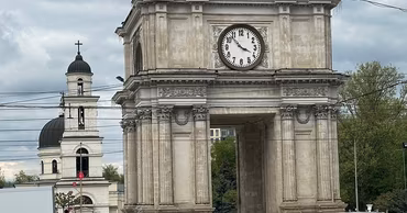 The Triumphal Arch in Chisinau with the Metropolitan Cathedral in the background and traffic in the foreground.
