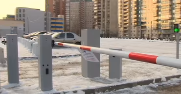 A parking lot with a barrier gate in a city setting during winter.