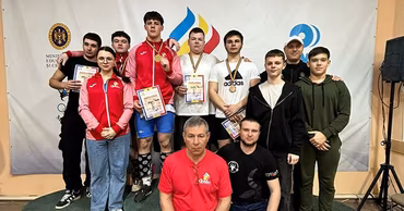Moldovan weightlifting athletes and coaches posing with medals and diplomas at a competition.
