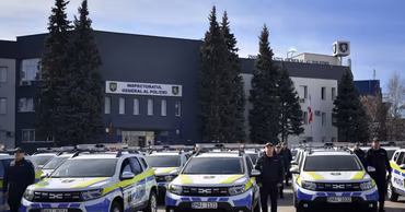 Moldovan police officers standing in front of the General Police Inspectorate building with patrol cars.