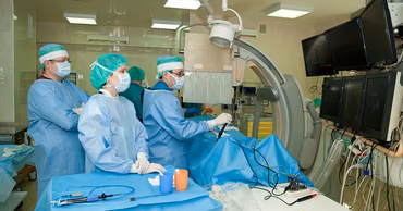 Medical team performing a procedure in a cardiology operating room with specialized imaging equipment.