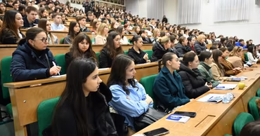 A large group of students sitting in a university lecture hall during a class.