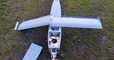 A crashed Parodia drone lying on the grass, showing its internal components and propeller.