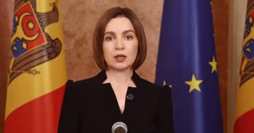 Moldovan President Maia Sandu speaking in front of Moldovan and European Union flags.