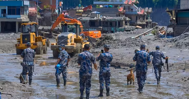 Rescue workers and heavy machinery operating in a mud-covered disaster zone in Nepal.