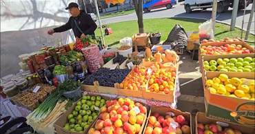 A vendor selling fresh fruits and vegetables at an outdoor market stall in Moldova.
