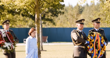 Maia Sandu walking with honor guards carrying wreaths during an official ceremony.