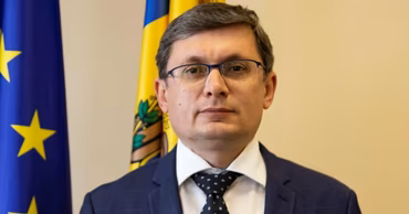 Igor Grosu, Speaker of the Parliament of Moldova, standing in front of flags.
