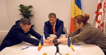 Ilan Shor and party members placing their hands together at a table with flags.