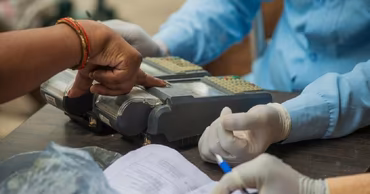 A person having their fingerprint scanned by an official wearing gloves.