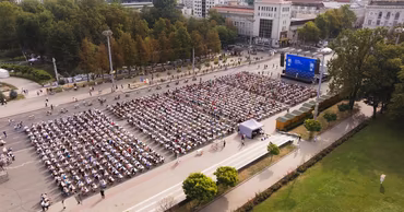 Aerial view of many people sitting at desks in a square participating in a dictation event.