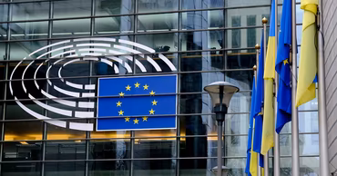 European Parliament building with European Union and Ukrainian flags displayed outside.