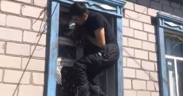 A rescuer climbing through a window to save a child from an apartment.