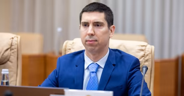Mihai Popșoi sitting at a table during an official meeting.