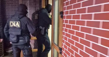 CNA officers in tactical gear entering a building during a search operation.
