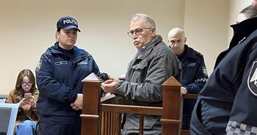 Ion Creanga standing in a courtroom dock surrounded by police officers.