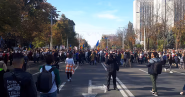 A crowd of people protesting on a street in Chisinau with the Ministry of Internal Affairs building.
