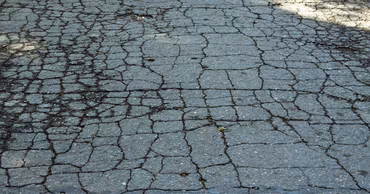 Close-up view of severely cracked and damaged asphalt road surface.