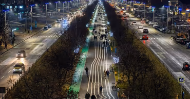Night view of Mircea cel Batran boulevard in Chisinau with traffic and pedestrian alley.