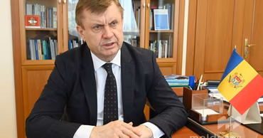 Valeriu Chiveri sitting at a desk with a Moldovan flag.