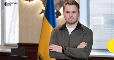 Ruslan Kravchenko standing in front of a Ukrainian flag.