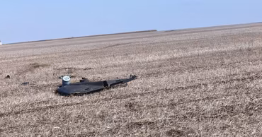 Debris of a Shahed drone lying in a dry field.