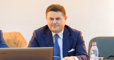 Oleg Tofilat sitting at a table with a laptop during a meeting.