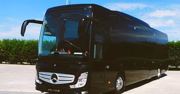 A black Atlas Tur passenger bus parked outdoors.