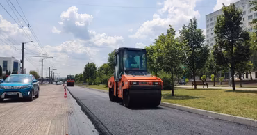 A road roller working on a street in Chisinau with traffic nearby.