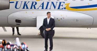 Volodymyr Zelenskyy standing in front of a plane with Ukraine written on the side.