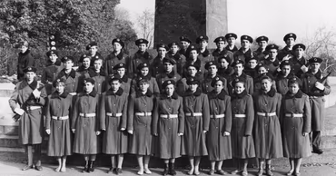 A group of students in military uniforms standing in formation outdoors.