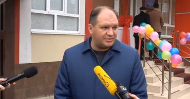 Ion Ceban speaking to journalists in front of a building decorated with balloons.