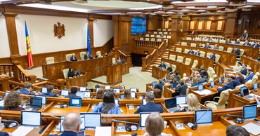 A wide shot of the Moldovan Parliament session hall with deputies at their desks.