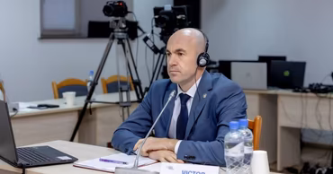 Victor Cazacu sitting at a table with a nameplate during a formal hearing.