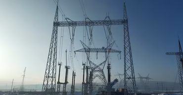High voltage power lines and electrical infrastructure in a snowy landscape.