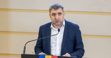 Lilian Carp speaking at a podium with the Moldovan flag.