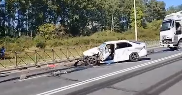 A heavily damaged white car on a highway after a traffic accident.
