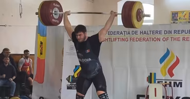 Moldovan weightlifter Tudor Bratu lifting a barbell during a competition.